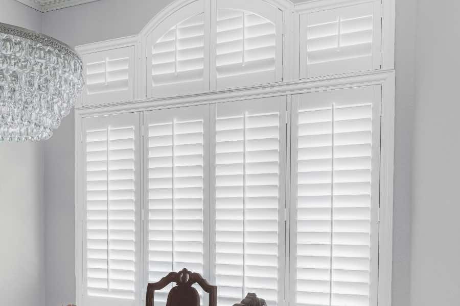 Polywood shutters on a large window in a neutral-colored dining room